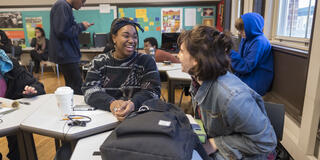 Two students in conversation with each other. Both are smiling.