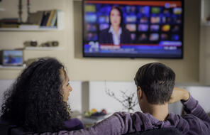 Photo of Two People Watching the News on TV