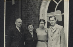 Four people pose for a photo in front of a large window.