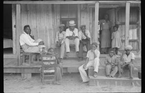 A photo of Black children and young adults on their porch. 
