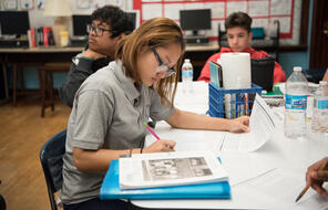 A student looks down at their paper with a pencil in hand filling out a graphic organizer.