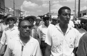 Dr. Martin Luther King, Jr. and Stokely Carmichael march with a crowd of people behind them.