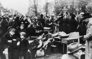 A crowd of people outside surrounded by their suitcases and other belongings