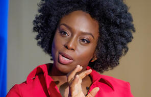 Chimamanda Ngozi Adichie poses for a portrait in a red shirt. 