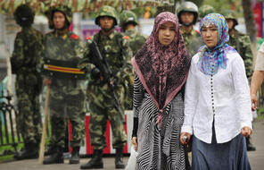 Two ethnic Uighur women pass Chinese paramilitary policemen