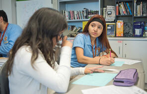 Two female students work at their desks. 