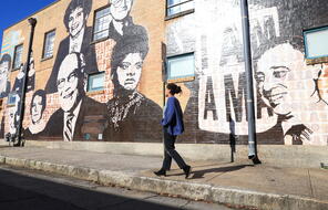 Civil Rights mural in background with someone walking on the sidewalk