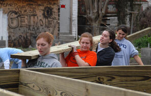 Volunteers from AmeriCorps carry a floor joist at a Habitat for Humanity home site in New Orleans.