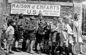 Children stand in front of a sign reading Maison d' Enfants USA