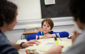 A female teacher engages with students in a classroom.
