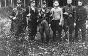 Black and white photograph of six Jewish partisans standing in a forest clearing