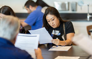 A women concentrates at a table while working on a handout