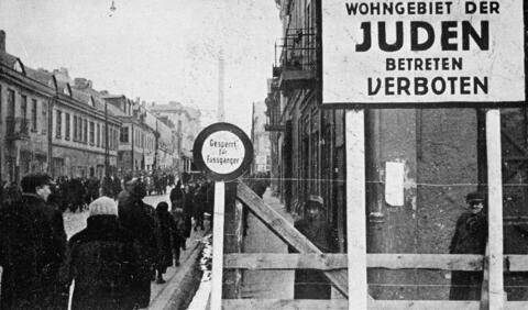 A German postcard shows the entrance to the Lódz ghetto in Poland. The sign reads, ""Jewish residential area—entry forbidden.""