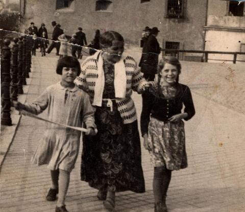 An elderly Sinti woman walks down a German street with her grandchildren in the 1930s.