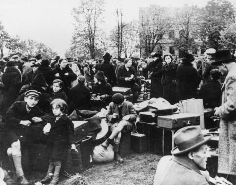 A crowd of people outside surrounded by their suitcases and other belongings