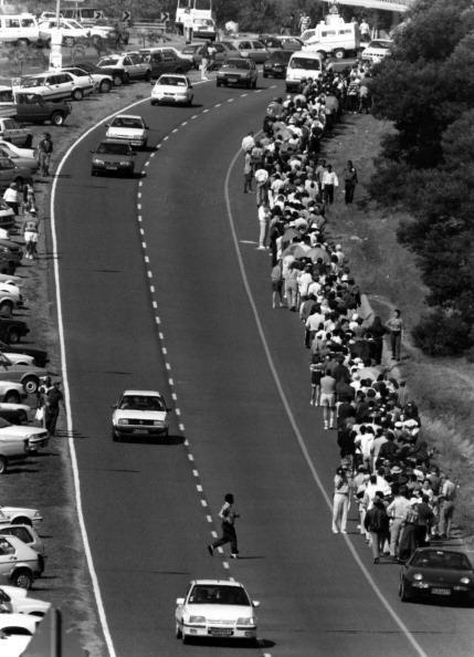 Long line of hundreds of South Africans along a busy highway.