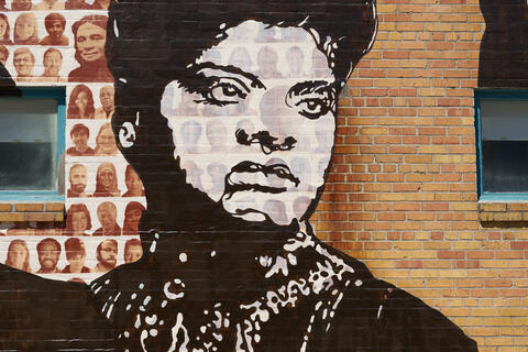 A black and white painting of Ida B. Wells on the Memphis Upstanders Mural, a painting on a brick wall in Memphis, TN.