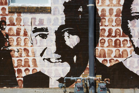 A black and white featured painting of John T. Fisher II on the Memphis Upstanders Mural, a painting on a brick wall in Memphis, TN.