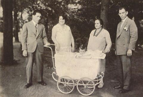 Rena's grandmother standing with family around a baby carriage. 