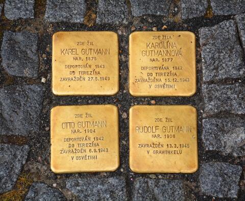 Four golden squares with inscriptions are built into the sidewalk.