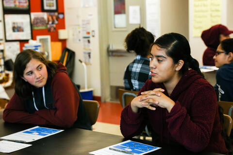 A student speaks while another listens attentively.
