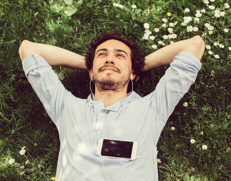 A person relaxes in the grass while listening to music.