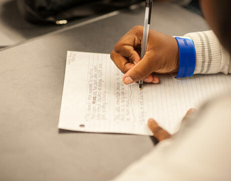 A close up of a student writing on a piece of paper.