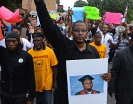 National President of Black Lawyers for Justice, carries a picture of Michael Brown as he leads demonstrators on a march.