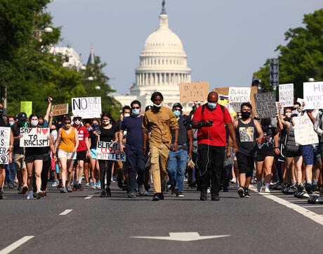 Demonstrators march down Pennsylvania Avenue with signs for Black Lives Matter